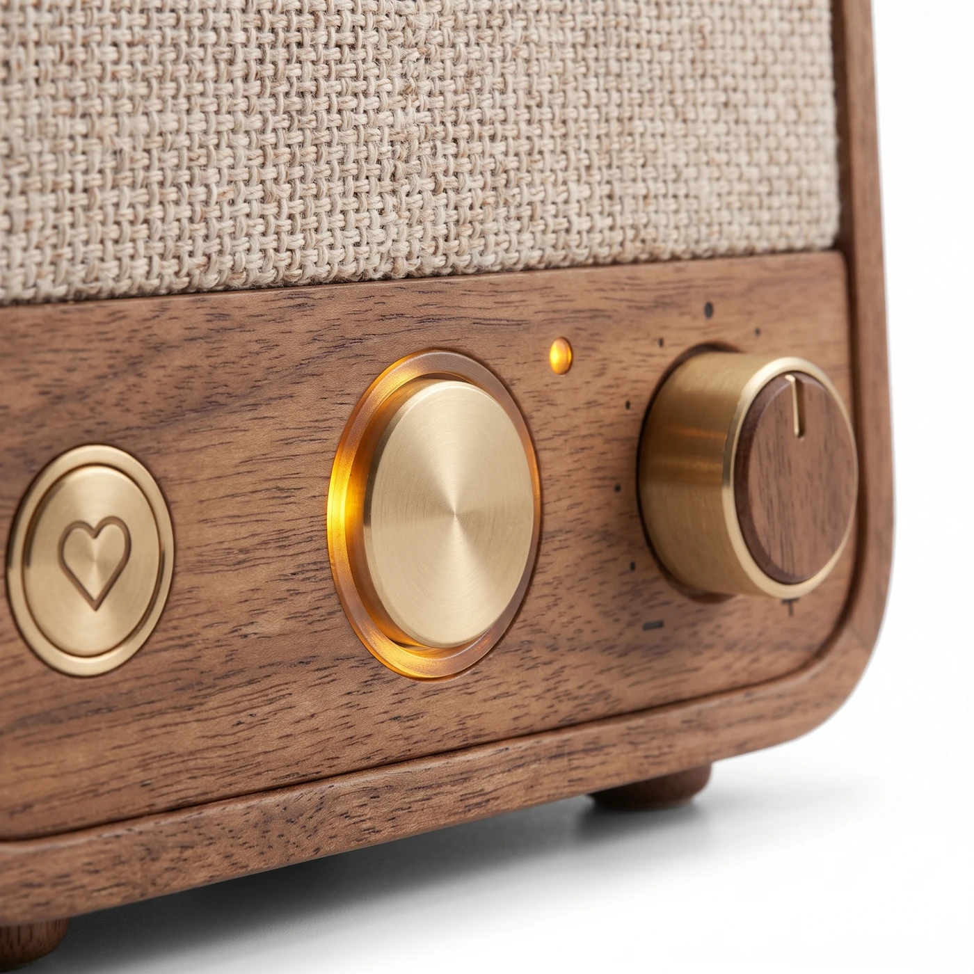 Close-up of the three controls: the heart button that plays family voice notes, the brass talk button ringed in amber, and the volume knob marked minus and plus.